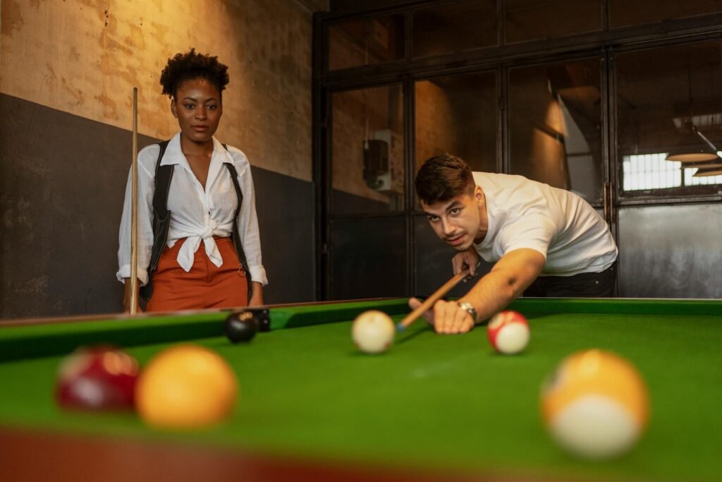 Two young adults engaging in a game of billiards in a stylish, vintage setting.